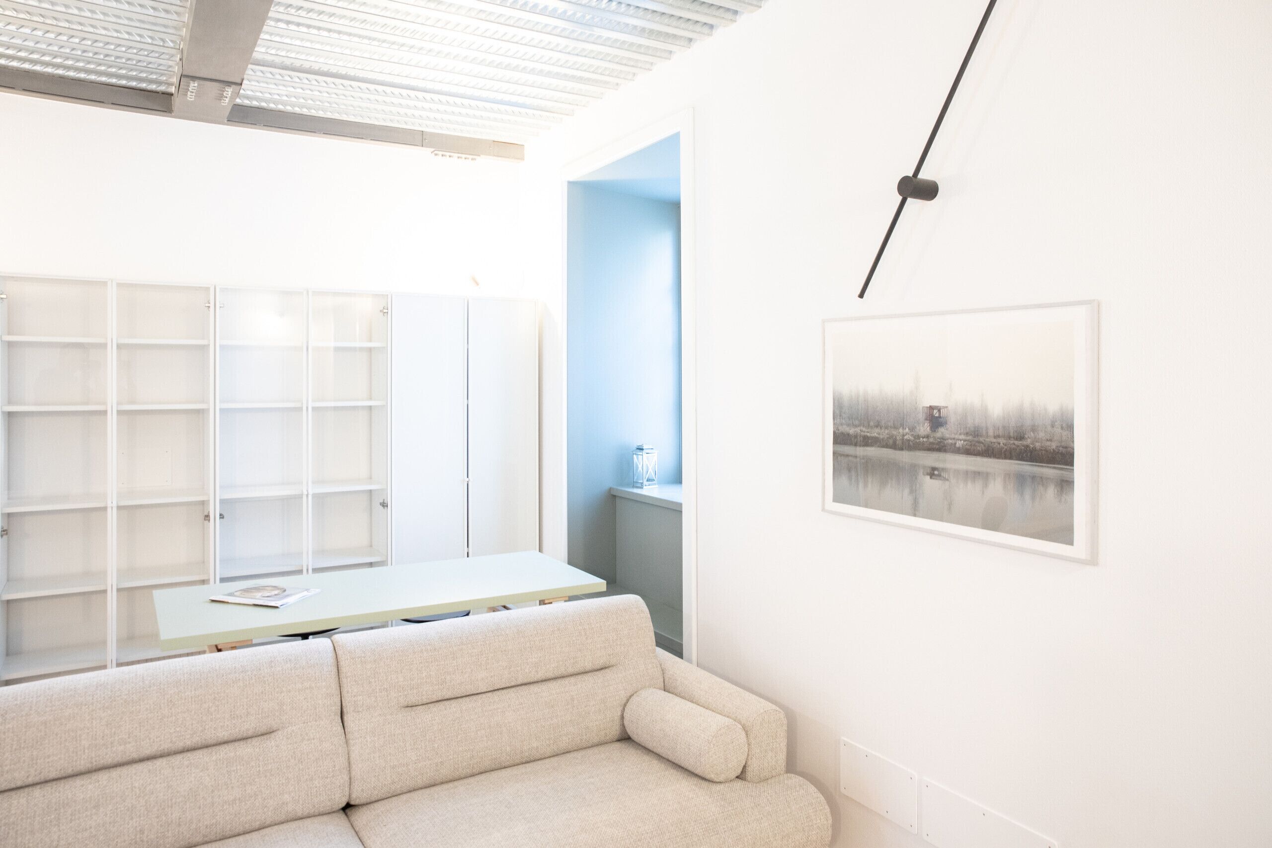 A modern, minimalist room with a sofa, a table, and a shelving unit.