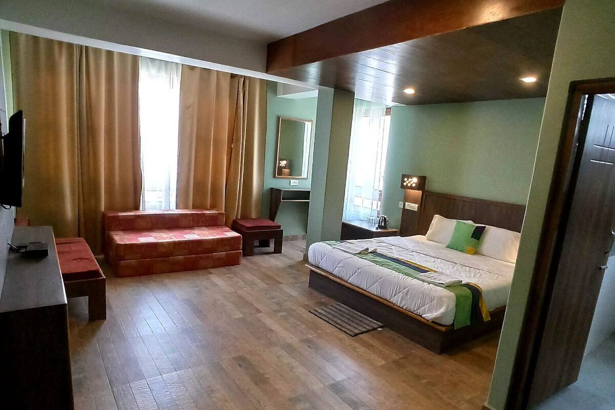 A hotel room with a bed, a desk, a chair, a small table, and a sofa.
