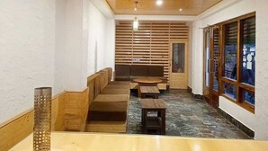 Un couloir étroit avec des marches en bois menant à un espace de repos équipé de bancs et de tables.