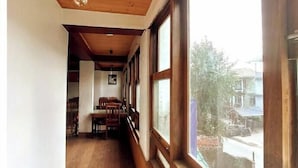Un couloir étroit, avec un plancher et des murs en bois, de grandes fenêtres d’un côté et un luminaire suspendu.