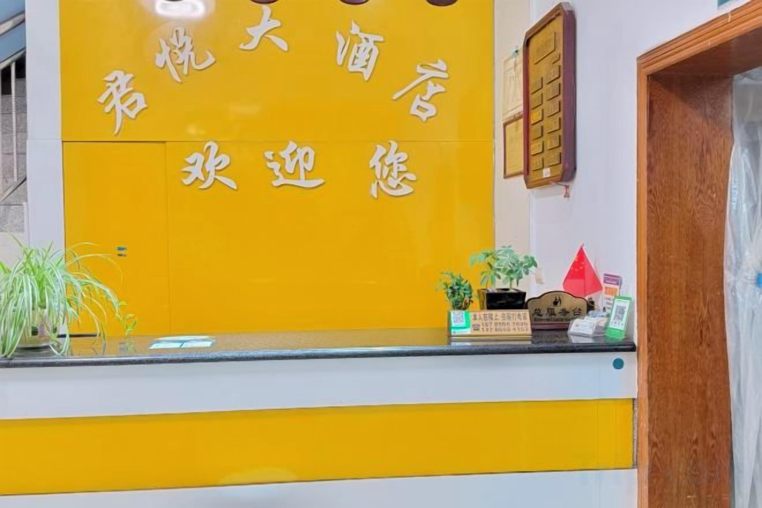 A reception desk with a yellow and white color scheme, a wooden door to the right, and a small plant on the counter.
