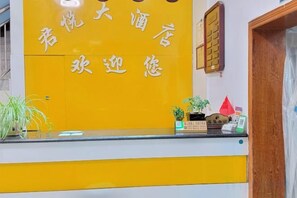 Un comptoir d’accueil aux couleurs jaune et blanc, une porte en bois sur la droite et une petite plante posée sur le comptoir.