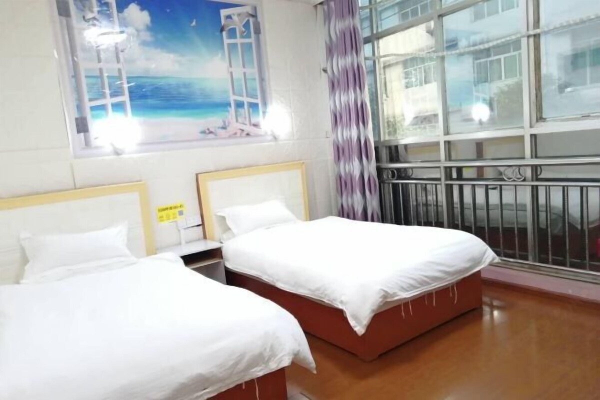 A hotel room with two beds, a window with a view of buildings, and a curtain.