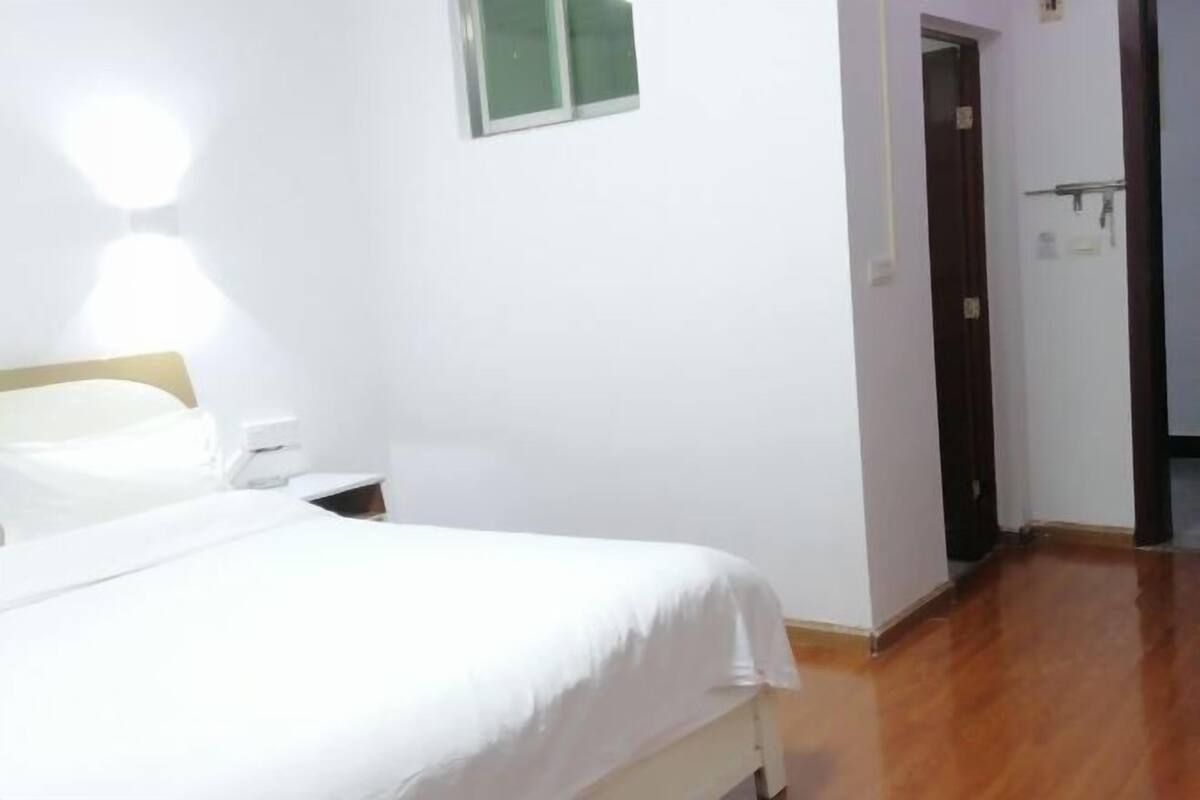 A hotel room with a bed, bedside table, and a door leading to another room.