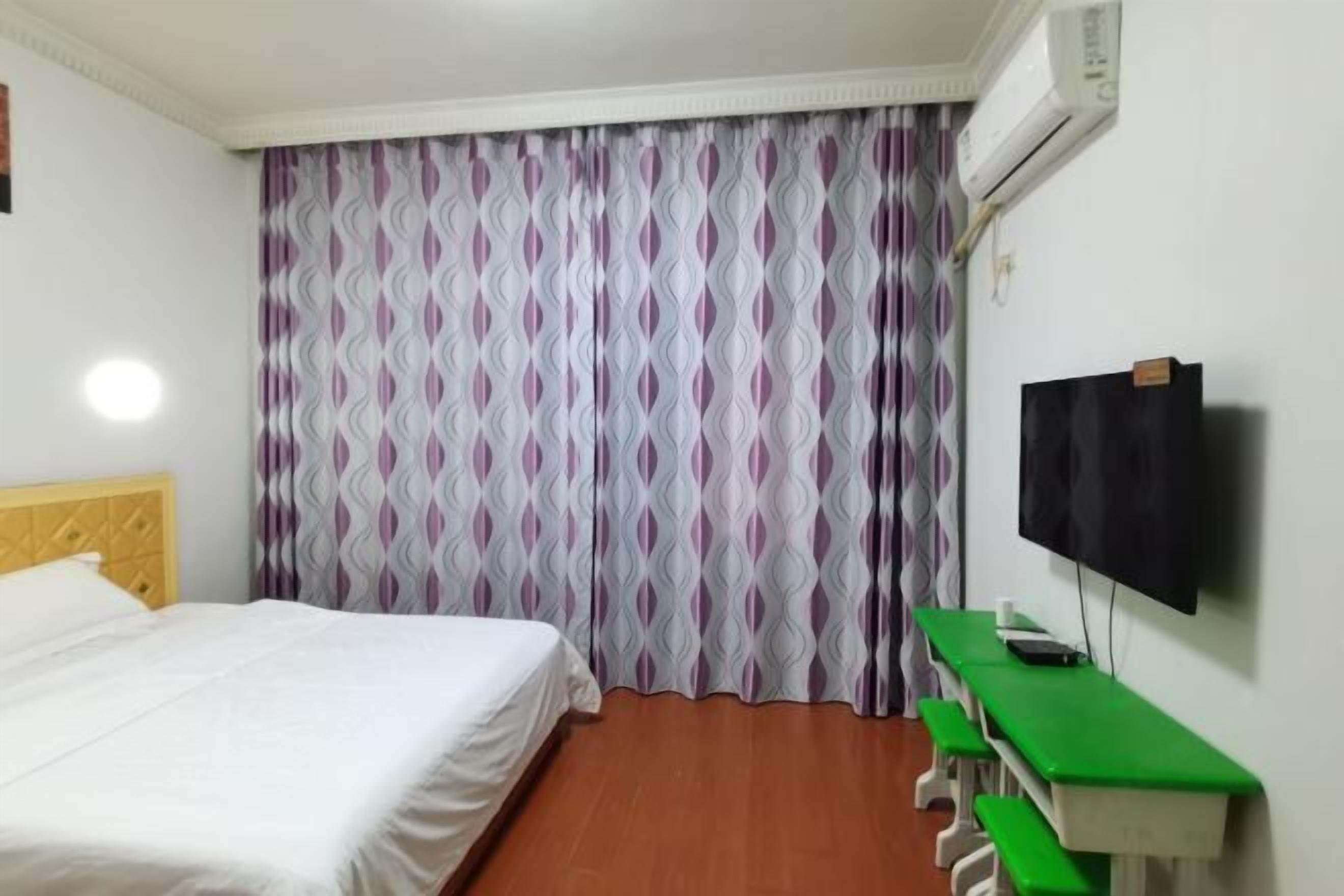 Een hotelkamer met een bed, een bureau en een televisie.