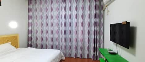 Ein Hotelzimmer mit Bett, Schreibtisch und Fernseher.