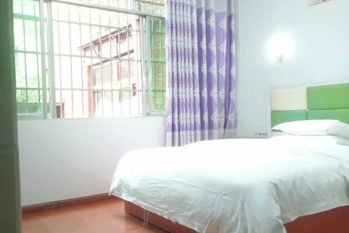 Ein Schlafzimmer mit Bett, einem Fenster mit Gitterstäben, einem Vorhang und einem grünen Kopfteil.
