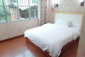 A bedroom with a bed, a window with bars, and a curtain.