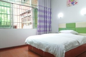 A bedroom with a bed, a window with bars, a curtain, and a green headboard.