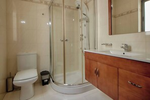 A bathroom with a toilet, a glass-enclosed shower, and a vanity with a sink and mirror.
