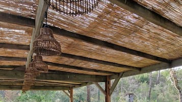 Enjoy a meal under the shade of a thatched roof, surrounded by lush gardens and comfortable seating.