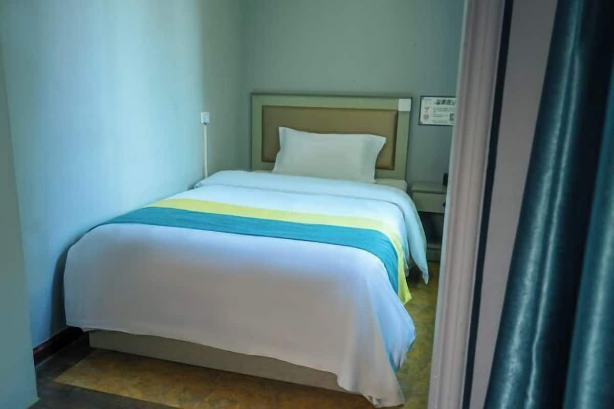A single bed with a headboard, a bedside table, and a wall-mounted sign.