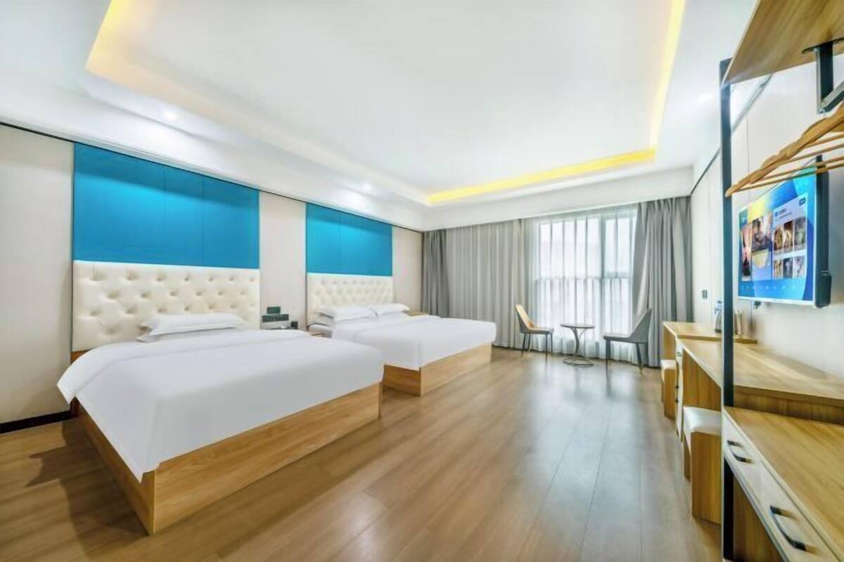 A hotel room with two beds, a TV, a desk, and a chair.