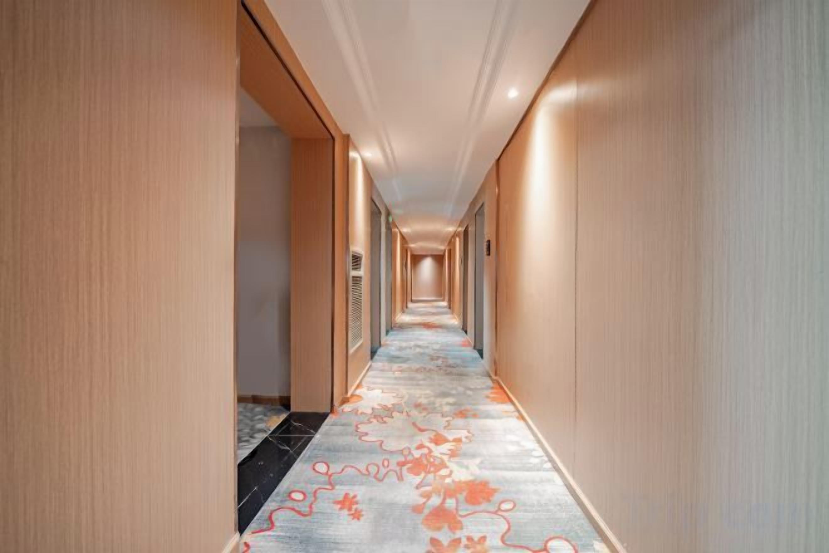 A long, narrow hotel corridor with a carpeted floor and wooden walls.
