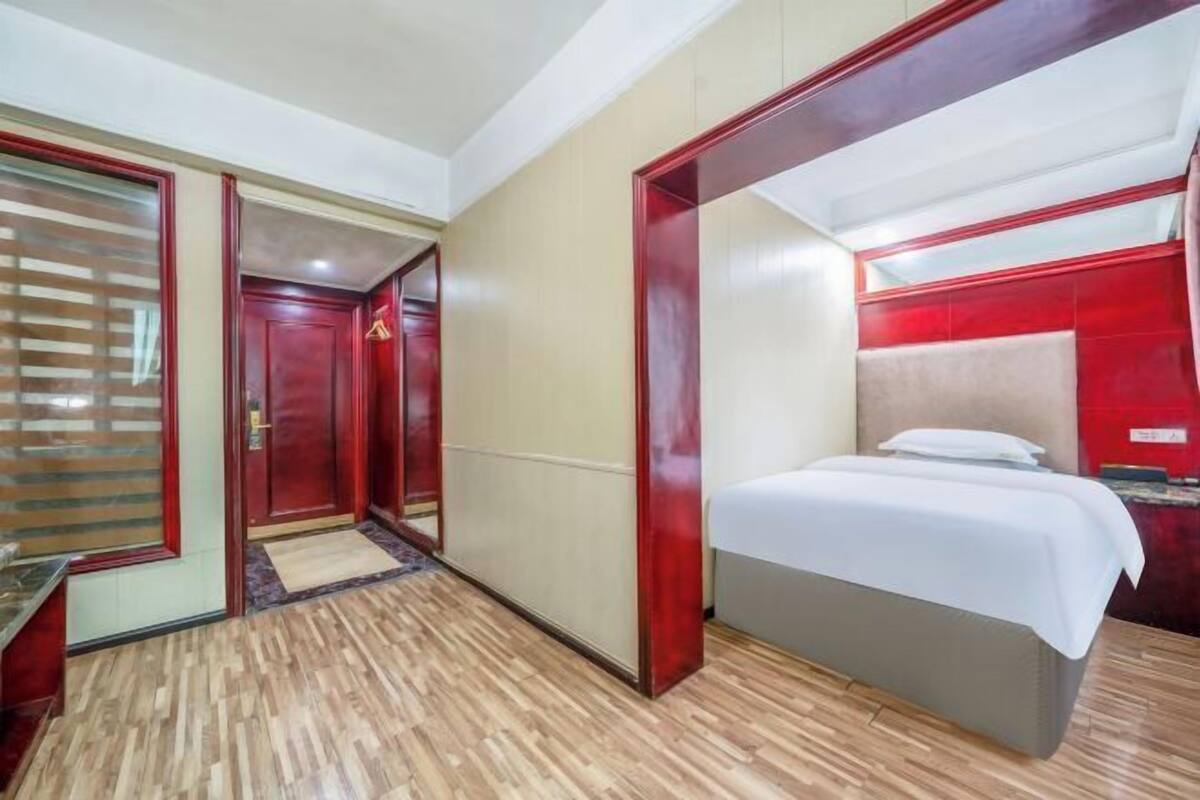 A hotel room with a bed, a wardrobe, and a door with a mirror.