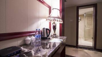 A hotel room with a marble countertop, a lamp, a kettle, a coffee maker, and a water dispenser.