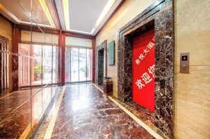 Un vestíbulo de hotel con piso de mármol, una puerta roja con caracteres chinos y un muro de cristal.