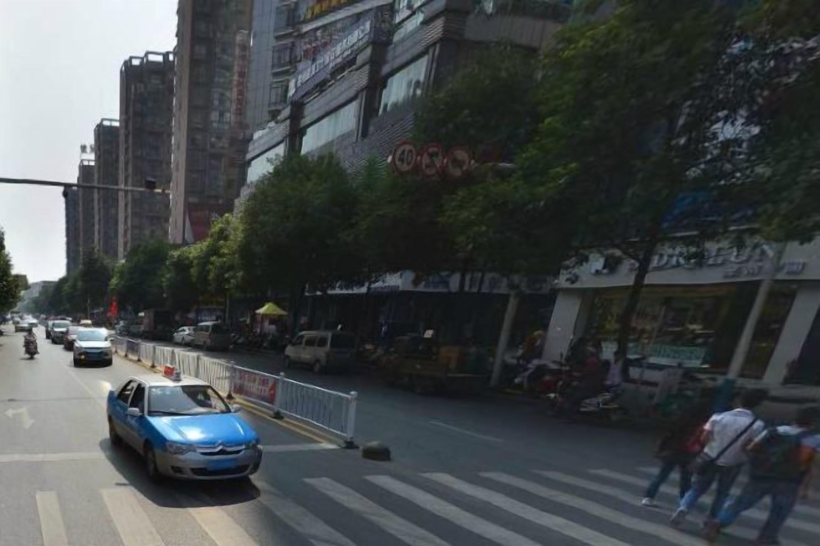 Une rue avec des véhicules, des piétons et des bâtiments.