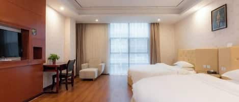 Una habitación de hotel con un escritorio de madera, dos camas, una silla y un ventanal grande.