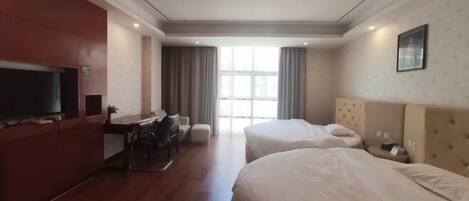 A hotel room with two beds, a desk, a chair, a TV, and a window with curtains.