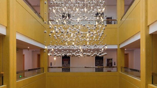 Een atrium met meerdere niveaus en een hanglamp in het midden.
