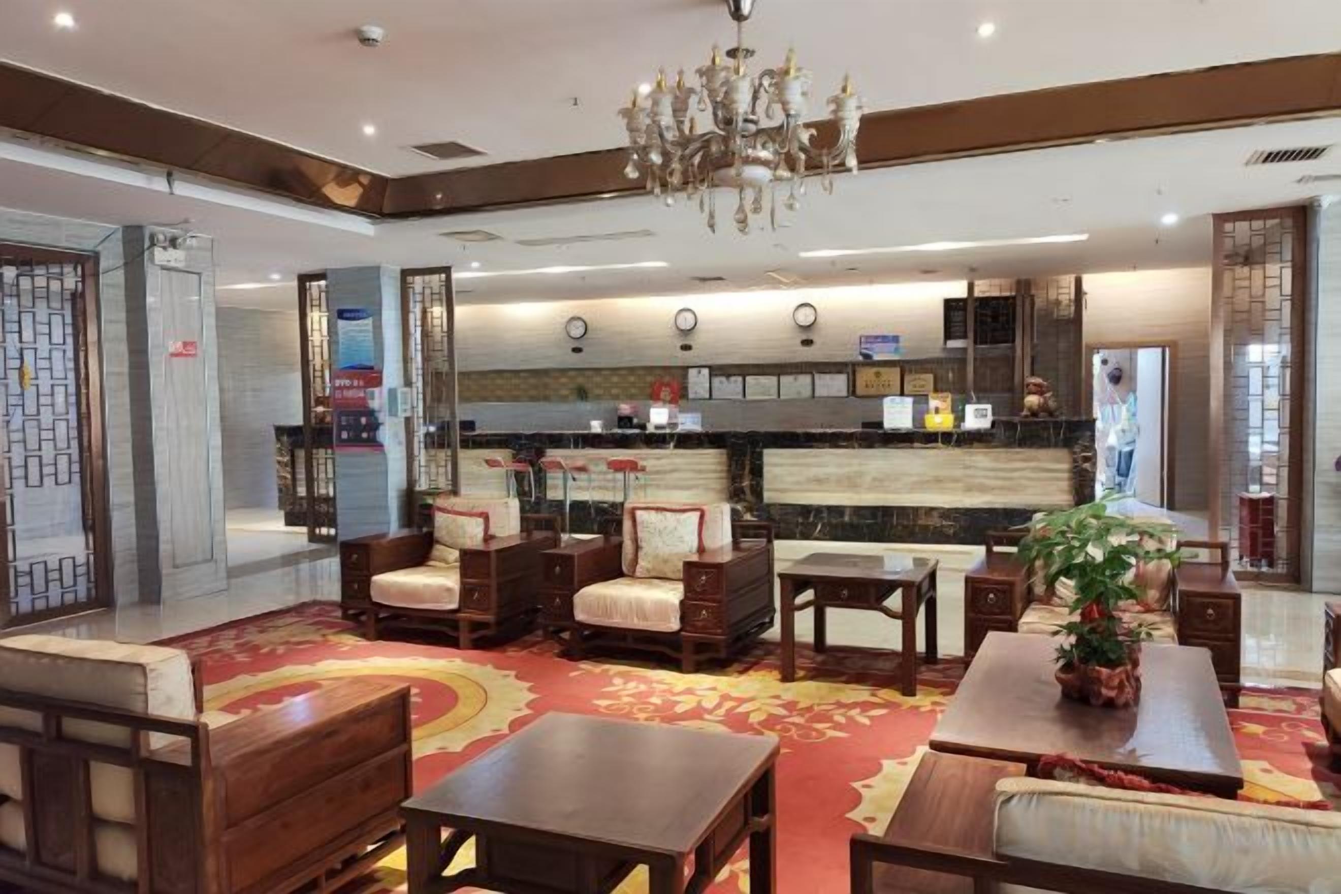 A hotel lobby with a reception desk, seating area, and a chandelier.