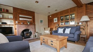 Una sala de estar acogedora con chimenea, un sofá azul, una mesa de centro de madera y un televisor.