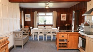 Una cocina acogedora con una mesa de comedor, sillas, armarios de madera y una ventana con cortinas.