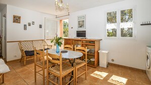 A dining area with a round table and four chairs, a small blue vase with flowers, and a television on a wooden cabinet. - 2 bedroom nice apartment in AFA (AFA)