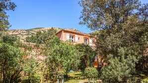 A rustic building with a red facade, surrounded by lush greenery and a mountainous backdrop. - 2 bedroom nice apartment in AFA (AFA)
