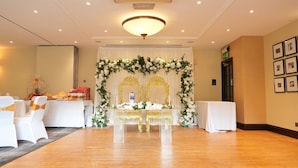 A wedding ceremony setup with a floral arch, two ornate chairs, and a table with floral arrangements. - Hotel Manor - Datchet (Slough)