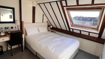 Un dormitorio con cama, escritorio, silla, ventana con vistas y radiador.