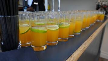 A row of glasses filled with a yellow beverage, possibly a cocktail, on a bar counter.