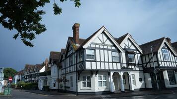 A traditional Tudor-style hotel with a prominent chimney, white and black timber framing, and a sign indicating it is a hotel.