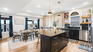 Una cocina moderna con una isla central, armarios oscuros y electrodomésticos de acero inoxidable.