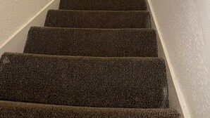 A carpeted staircase with a handrail, white walls, and a light fixture at the top. - F2S Serviced 2Bed House Wi-fi, Netflix, Parking, Train station nearby. Holiday! (Derby)