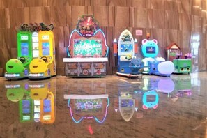 Una hilera de máquinas de videojuegos sobre un suelo pulido que refleja sus imágenes.
