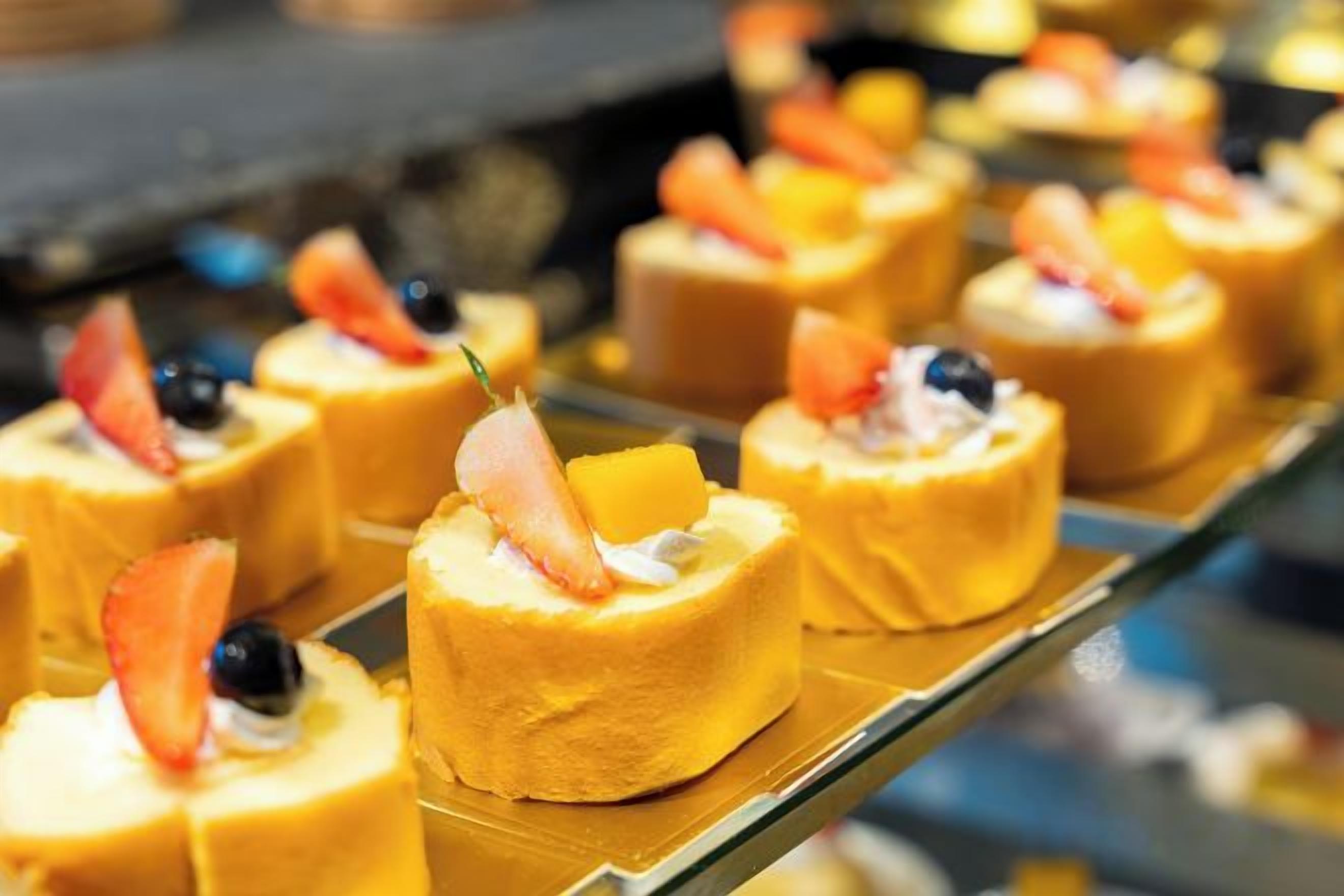 A display of small, round desserts topped with fruit and a toothpick.