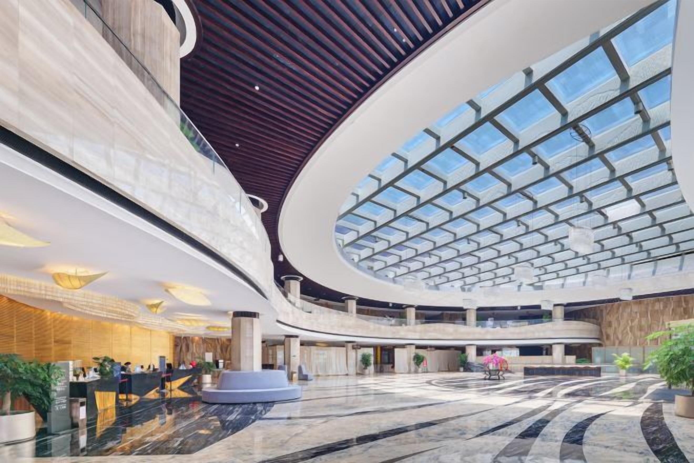 A spacious lobby with a high ceiling, a central atrium, and a reception desk.