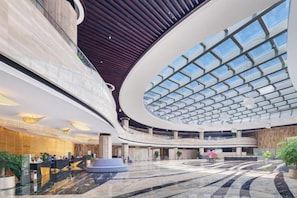 A spacious lobby with a high ceiling, a central atrium, and a reception desk. - Fanhua Hotel (Quanzhou)