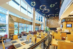 Un restaurante moderno con techos altos, ventanas amplias y una zona central de mesas.