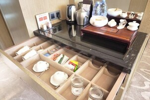 Habitación de hotel con minibar, cafetera, hervidor de agua y tetera.