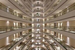 Un atrio de varios niveles con balcones, pisos reflectantes y un espacio central abierto.