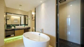 Un baño moderno con una bañera independiente, un espejo grande y un box de ducha de vidrio.