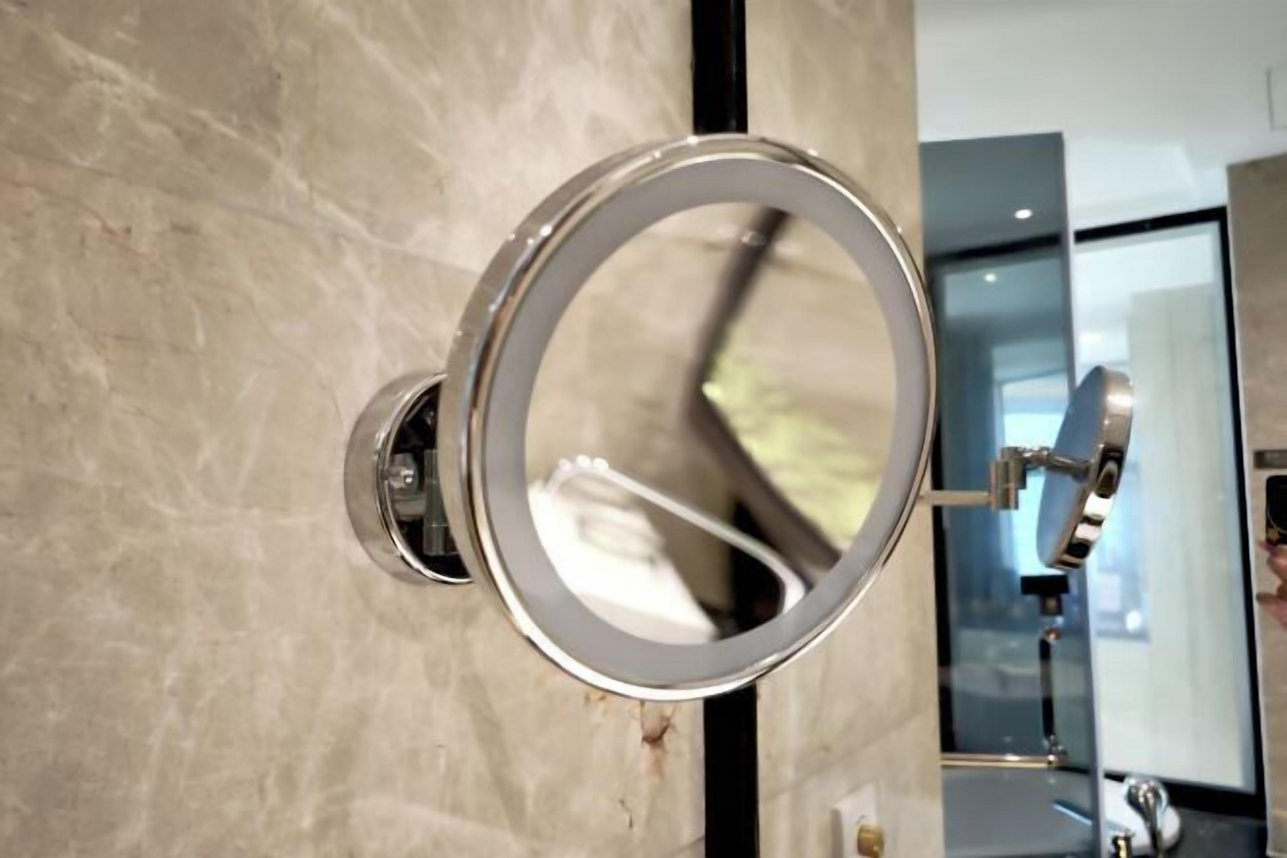 A bathroom with a wall-mounted mirror and a chrome faucet.