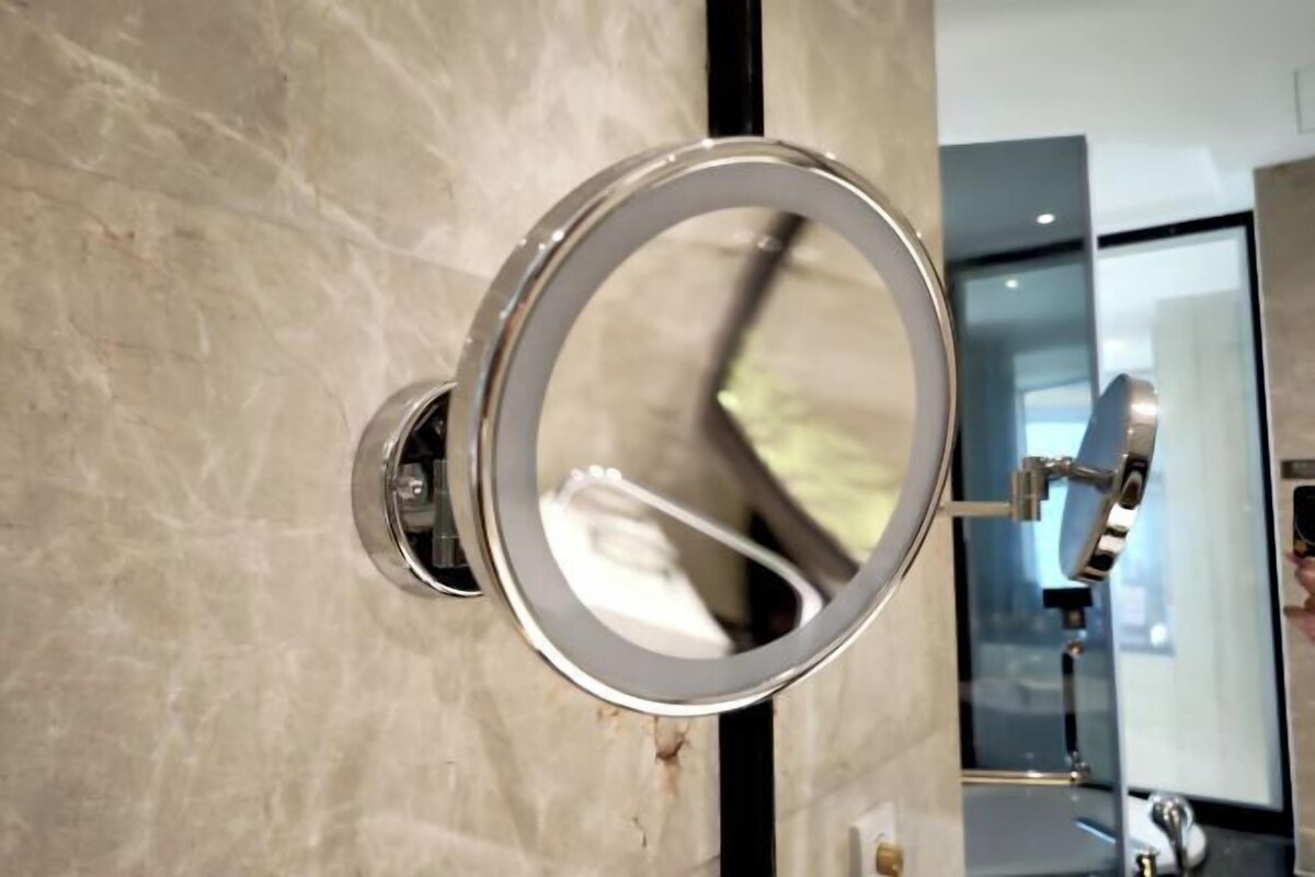 A bathroom with a wall-mounted mirror and a chrome faucet.