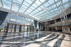 A spacious atrium with a high ceiling and a glass roof, featuring a polished marble floor and modern furnishings. - Fanhua Hotel (Quanzhou)