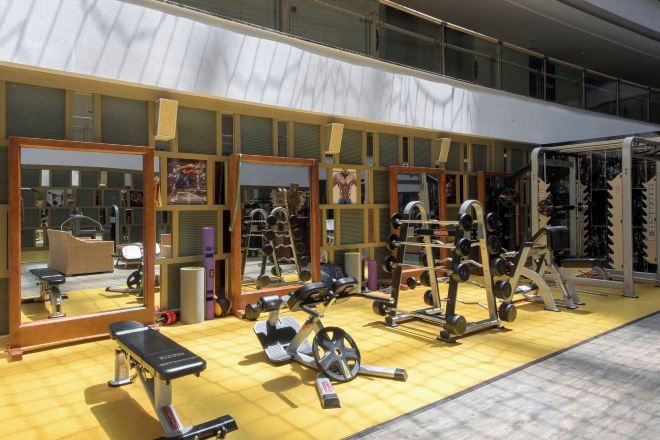 A gym with exercise equipment, mirrors, and a yellow floor.