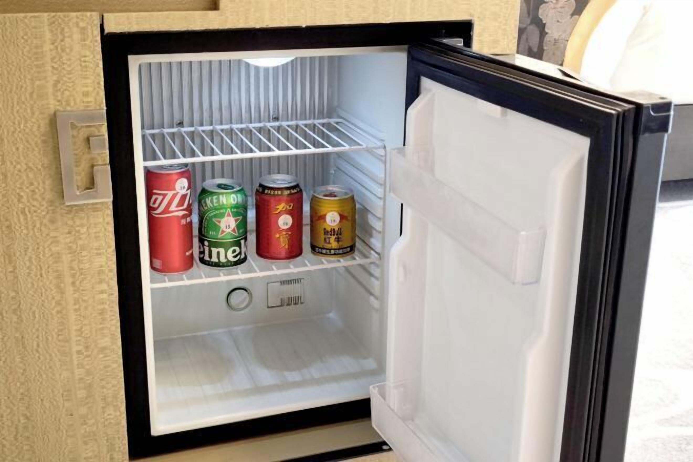 Un mini refrigerador con cuatro latas de bebida.