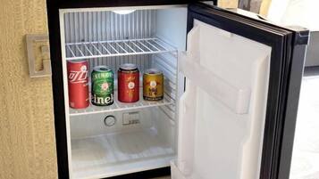 Un mini refrigerador con cuatro latas de bebida.